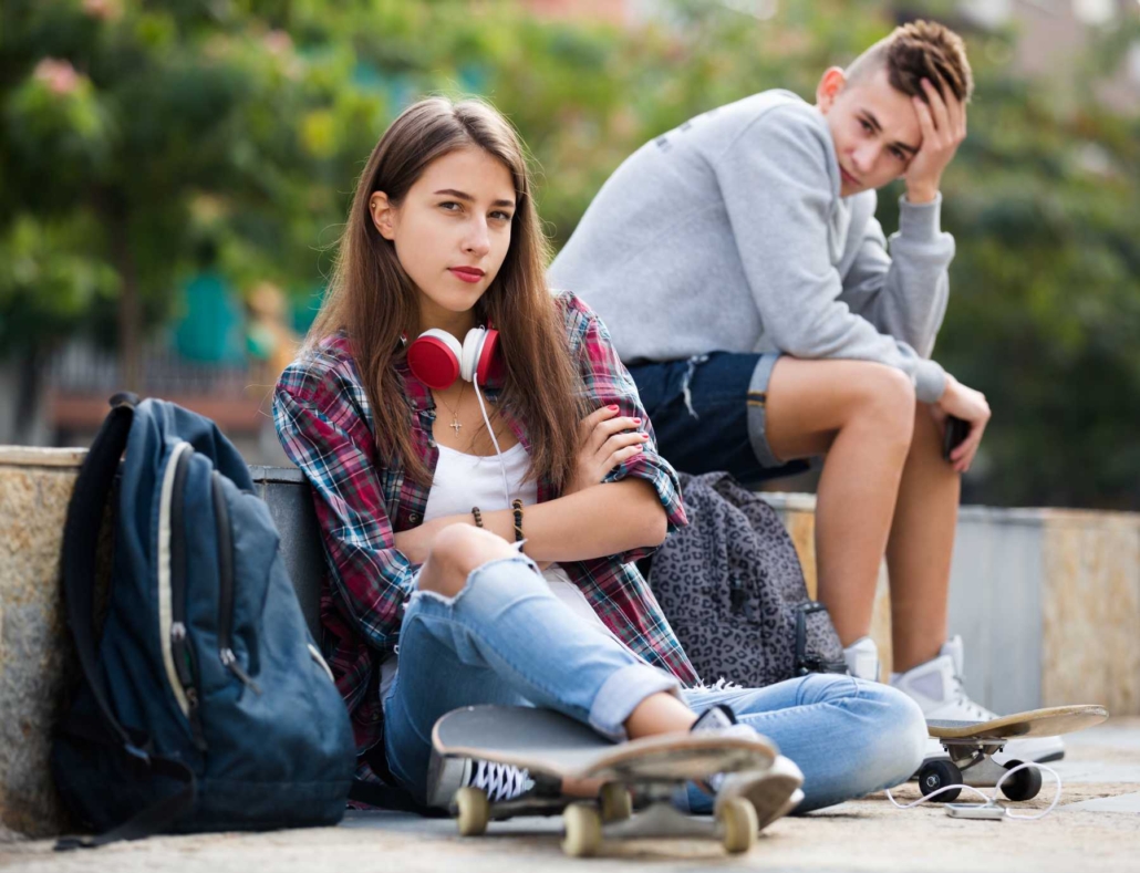 teen sitting with arms crossed and skateboard
