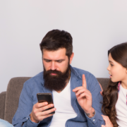 Dad holds up finger to teen as he looks at phone