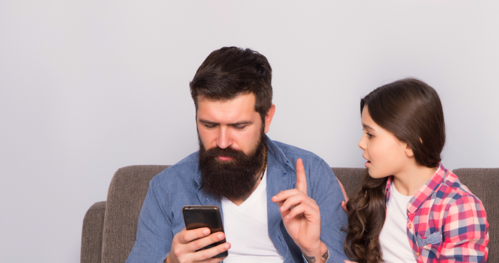 Dad holds up finger to teen as he looks at phone
