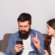 Dad holds up finger to teen as he looks at phone
